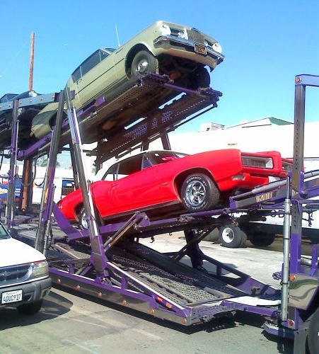 Dennis Buys Classic Cars car hauler with red Pontiac GTO and Plymouth Barracuda