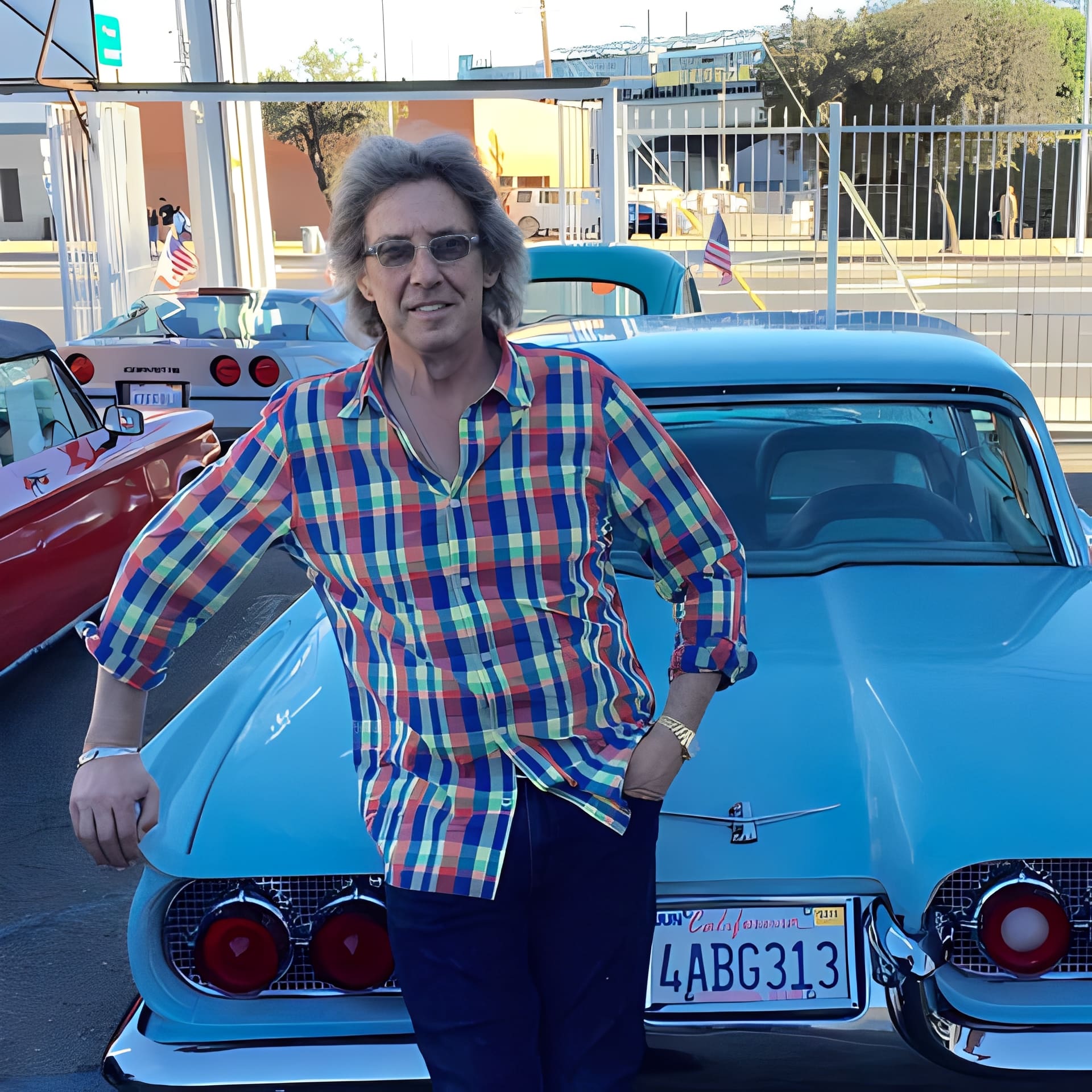 Man standing by classic blue car.