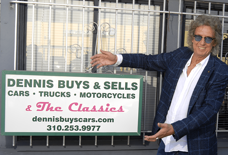 Man presenting car dealership sign outdoors.