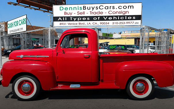 Red vintage truck parked at car dealership.
