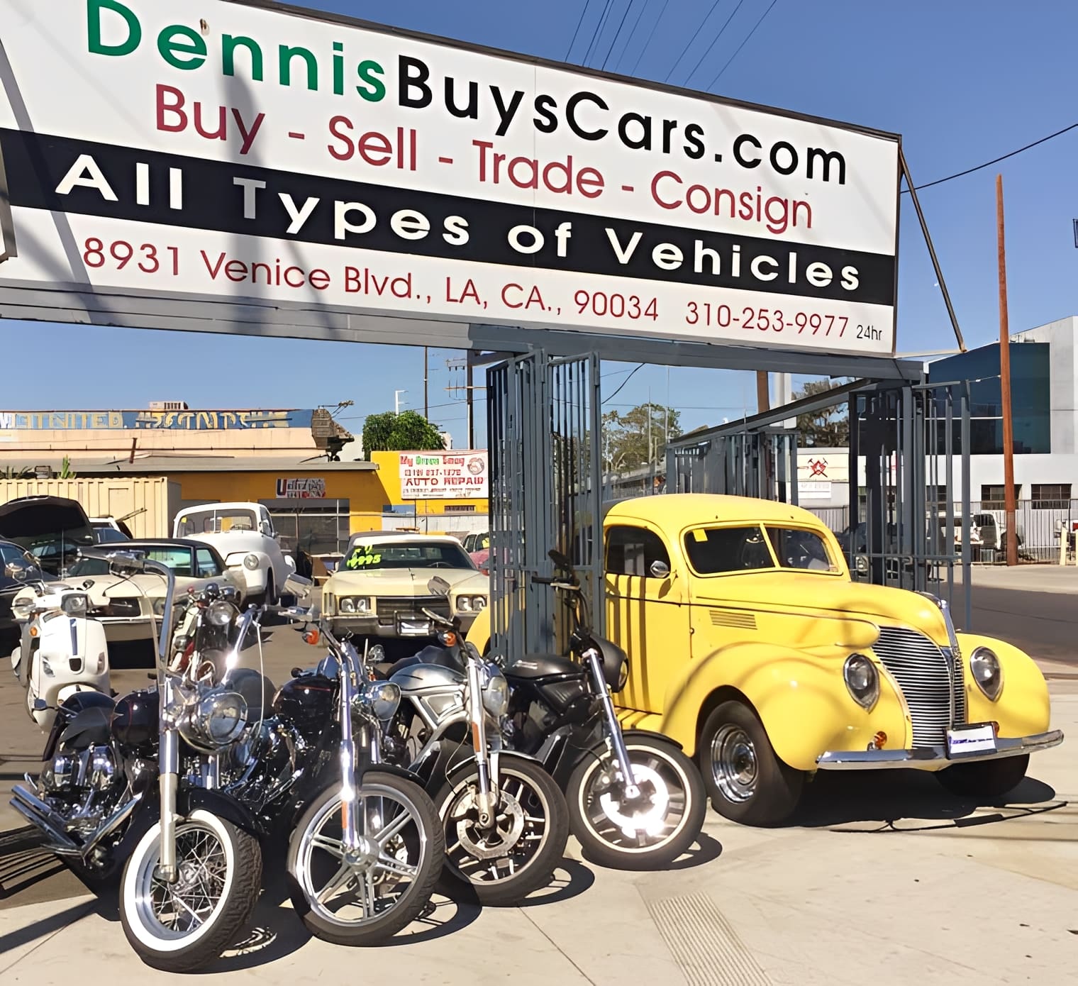 Motorcycles and vintage car at dealership entrance.