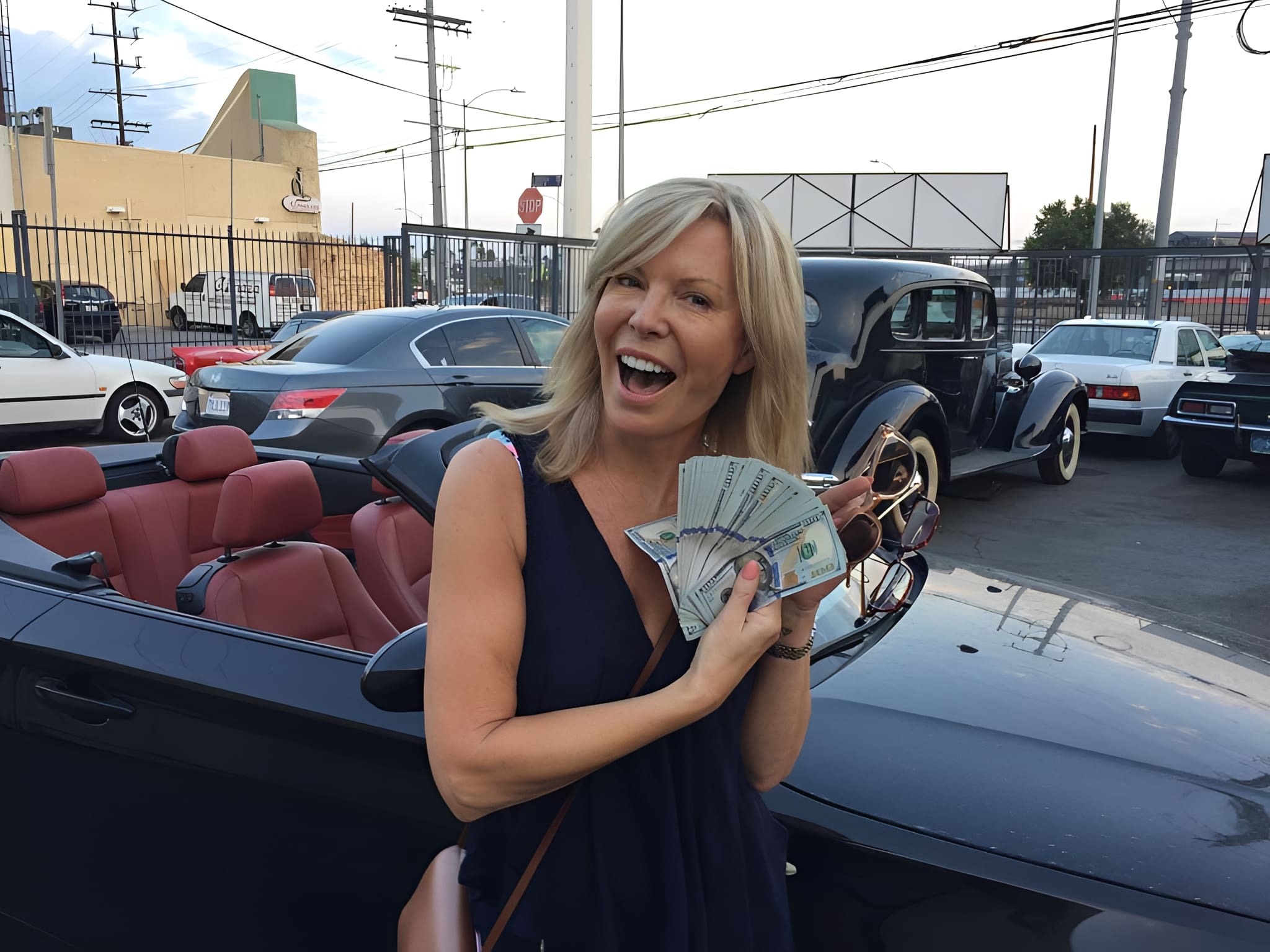 Woman holding money by convertible car.