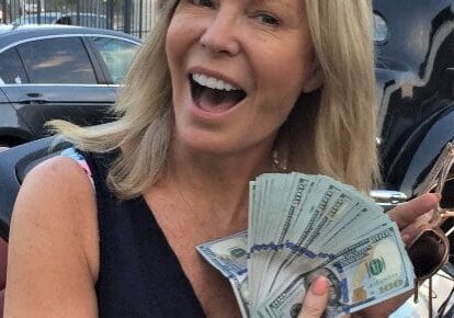 Woman smiling, holding a fan of cash.