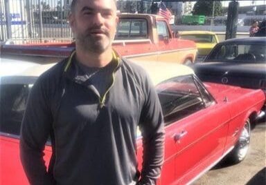 Man standing in front of classic cars.