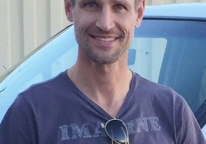 Man smiling in front of a car.