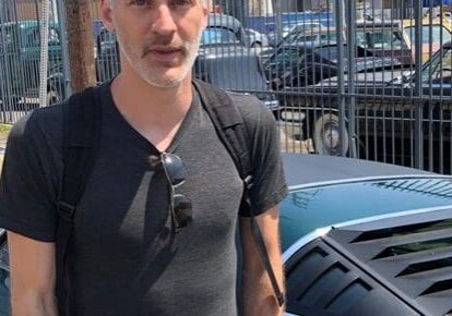 Man standing beside a parked sports car.
