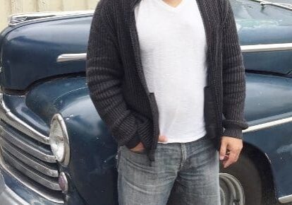 Man standing next to vintage blue car.