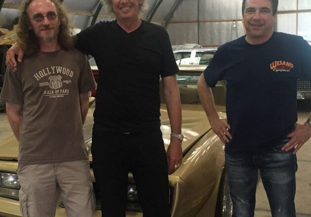 Three men posing in a garage.
