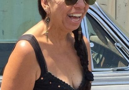 Smiling woman with braided hair, wearing sunglasses.
