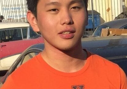 Young man in an orange shirt outdoors.