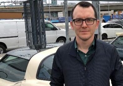 Man standing next to a parked car.