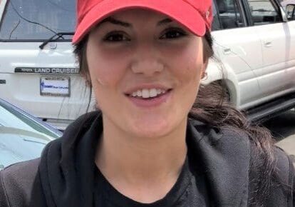 Woman wearing red cap in parking lot.