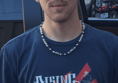 Man wearing blue shirt and bead necklace.