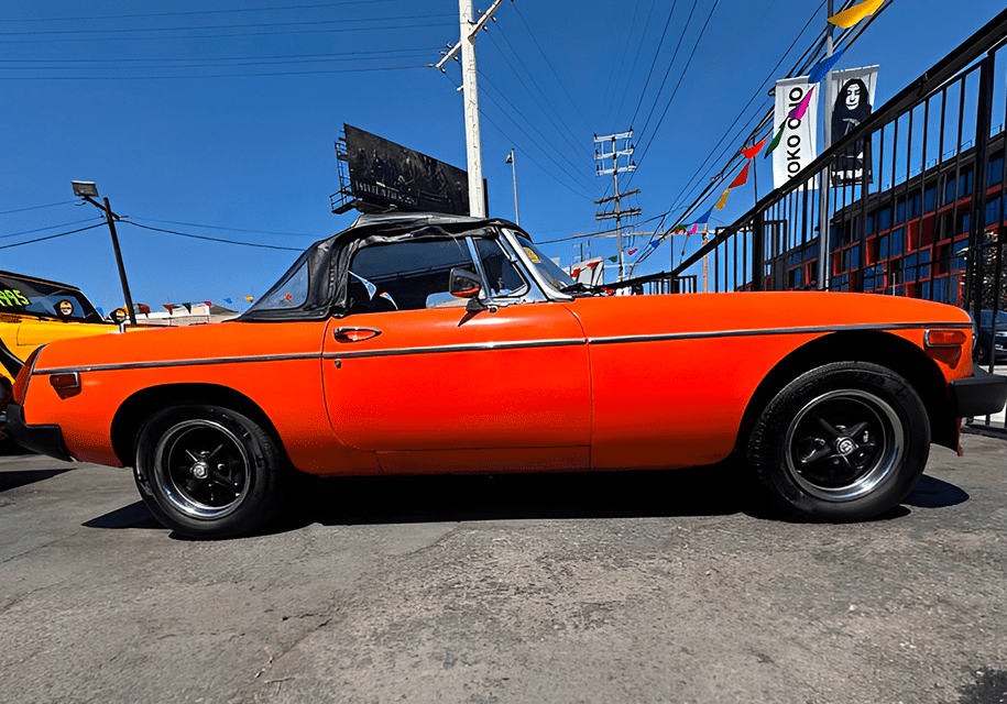 Orange vintage convertible car parked on street.